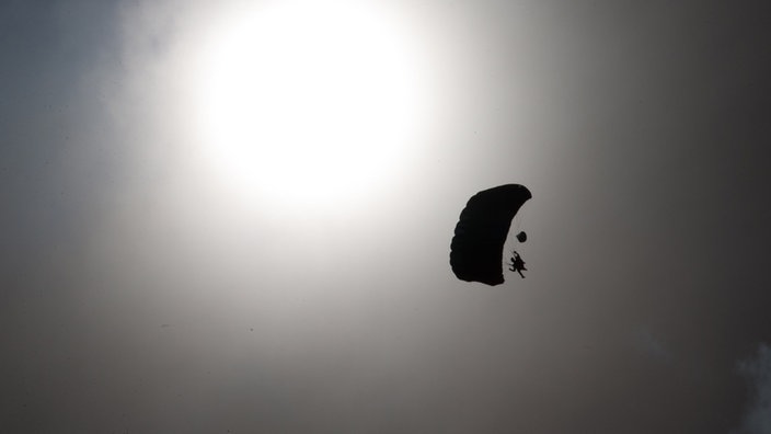 Ein Fallschirmspringer ist über dem Flugplatz in Bad Sassendorf  am Himmel zu sehen