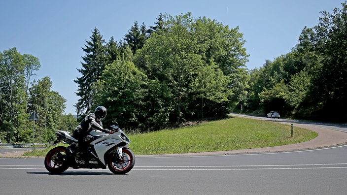Ein Motorradfahrer fährt in der Eifel durch eine Kurve