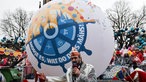 Das Motto für die nächste Session "·Morje es, wat do drus mähs!" steht auf einem Ball, welches vom Zugleiter des Kölner Rosenmontagszug, Marc Michelske, präsentiert wird. 