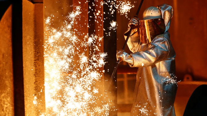 Ein Stahlarbeiter von Thyssenkrupp steht in Duisburg inmitten von Funken 