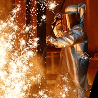 Ein Stahlarbeiter von Thyssenkrupp steht in Duisburg inmitten von Funken 