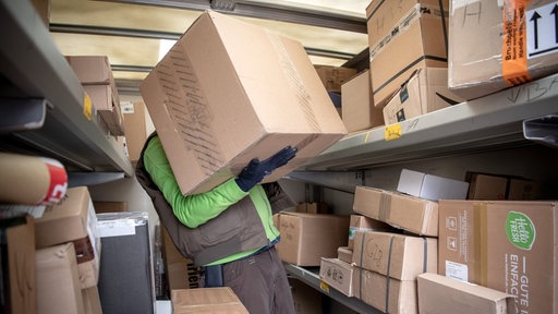  Ein Paketbote lädt Pakete in einen Transporter.