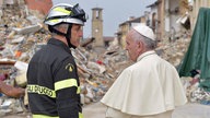 Papst Franziskus spricht mit einem Feuerwehrmann vor den Trümmern der vom Erdbeben betroffenen Stadt Amatrice