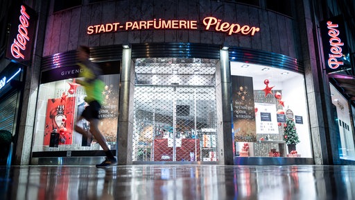 Ein Mann läuft an einer geschlossenen Fililae der Parfümerie Pieper an der Königsallee vorbei