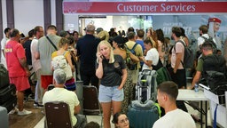 Passagiere stehen vor dem Customer Service am Flughafen 