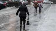 Passanten gehen vorsichtig auf einer vereisten Straße