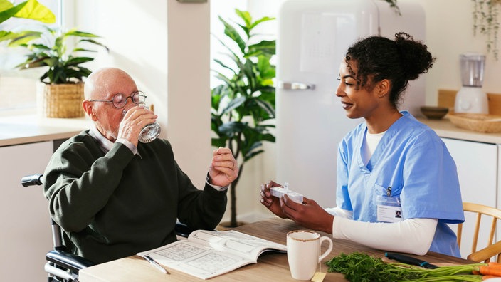 Krankenschwester gibt älterem Mann seine Medizin