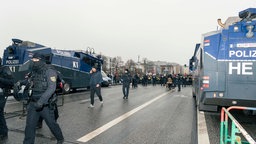 Wasserwerfer der Polizei, im Hintergrund Demonstranten