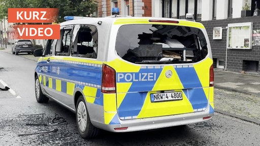 Polizeifahrzeug mit eingeschlagenen Scheiben und herumliegenden Scherben
