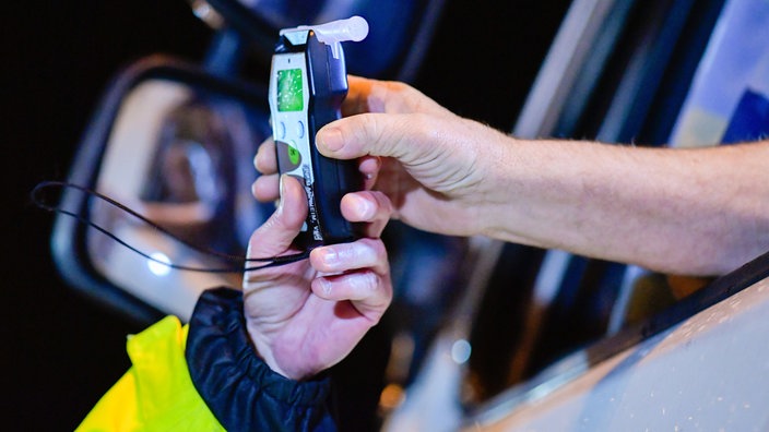 Symbolbild: Polizisten reichen Fahrer Alkoholmessgerät