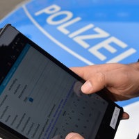 Ein Polizeikommissar demonstriert wie das Tablet für den Einsatz- und Streifendienst funktioniert