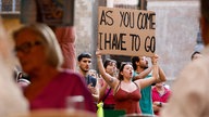 Eine Frau hält ein Schild mit der Aufschrift "As you come - I have to go" bei der Demo gegen Massentourismus hoch