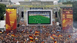 Tausende Zuschauer verfolgen auf der Fanmeile am Brandenburger Tor in Berlin das WM-Fußballspiel zwischen Deutschland und Argentinien
