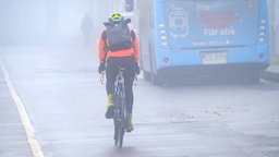 Radfahrer mit leuchtender Kleidung im Nebel