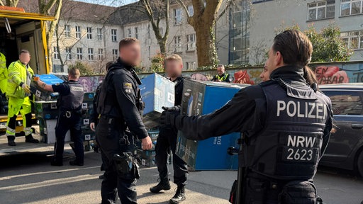 Polizeibeamte beladen während der Razzia einen LKW