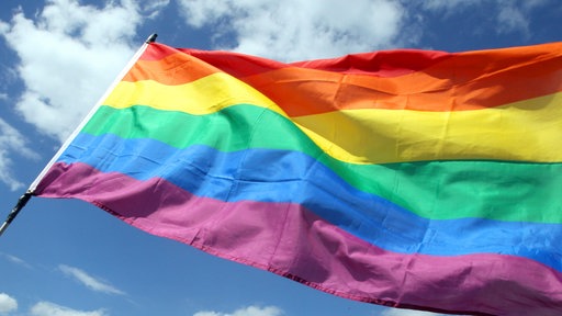 Regenbogenflagge vor blauem Himmel