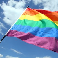 Regenbogenflagge vor blauem Himmel