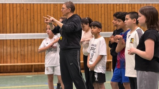 Lehrerin kommuniziert mit Schülern und Schülerinnen in der Sporthalle