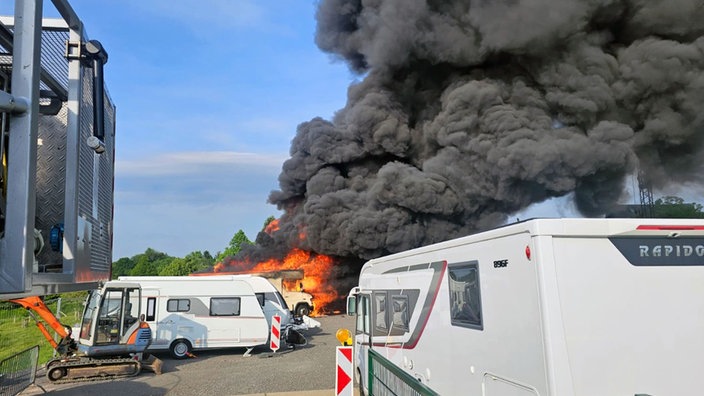 Eine große, schwarze Brandwolke und Feuer über mehreren Wohnwägen