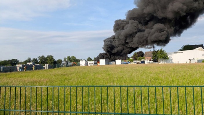 Eine große, schwarze Brandwolke über mehreren Wohnwägen aus einiger Entfernung aufgenommen.