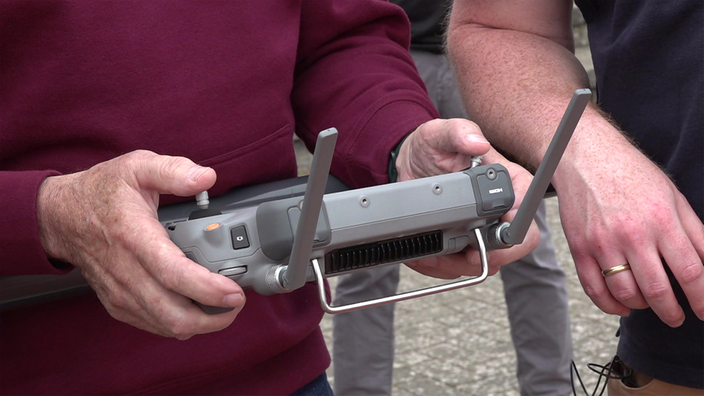 Ein Mann hält die Fernbedienung einer Drohne in der Hand.