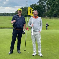 Zwei Männer stehen mit Golfschlägern auf einem Golfplatz vor 