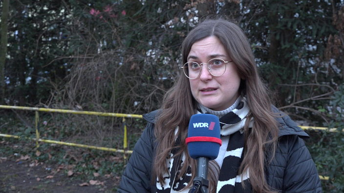 Eine junge Frau mit einer Brille wird mit einem Mikrofon interviewt.