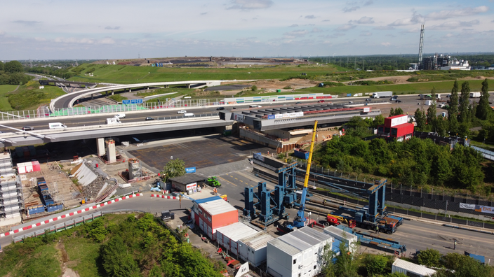 Die neue Leverkusener Rheinbrücke an einer stelle über der Autobahn. Dort stehen ein Kran und noch Bauteile der Brücke. 