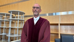 Schmaler, großer Mann in roter Richter-Robe