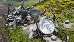 Ein Schrotthaufen auf einer grünen Wiese mit Lampen von einem Flutlichtmast