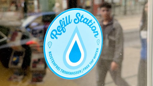 Ein hellblauer Aufkleber auf einem Schaufenster mit der Aufschrift "Refill Station"