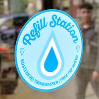 Ein hellblauer Aufkleber auf einem Schaufenster mit der Aufschrift "Refill Station"