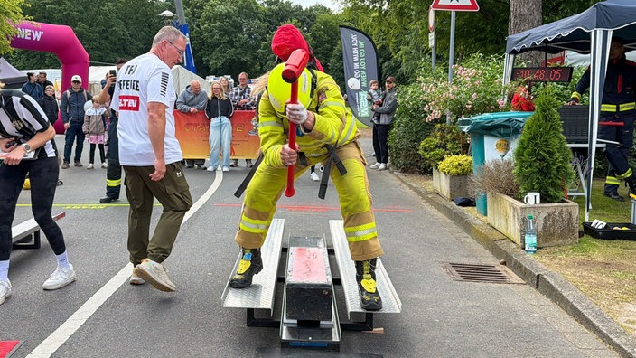 Feuerwehrmänner nehmen an einer Challenge mit Vorschlaghammern teil