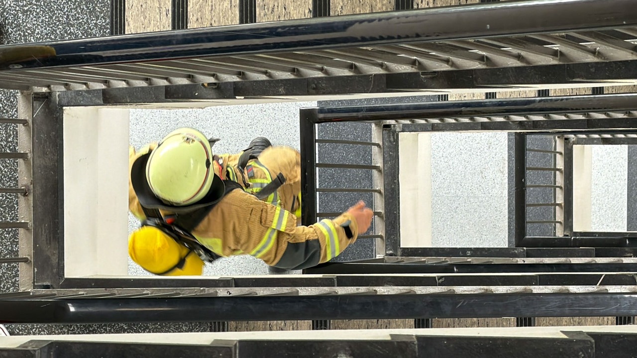 Ein Feuerwehrmann läuft in Ausrüstung Treppen hoch