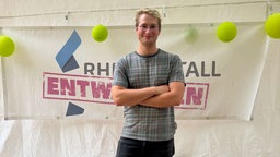 Jonah Fischer der Organisator steht vor einem Plakat mit der Aufschrift  "Rheinmetall entwaffnen"