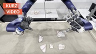 Roboterhände puzzeln Scherben zusammen.