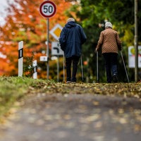 Rentner-Ehepaar spaziert im Herbst auf einem Gehweg