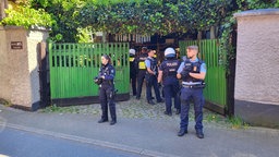 Viele Polizisten stehen vor dem Haus an das rechtsextreme Flaggen gehängt wurden.