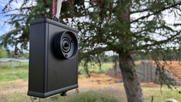 Schwarzes Ultraschalllockgerät in einem Garten mit Bäumen im Hintergrund