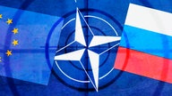 Die Fahnen von EU und Russland auf NATO-Fahne mit Fadenkreuz