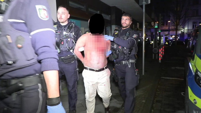 Polizisten führen einen Mann in Handschellen ab