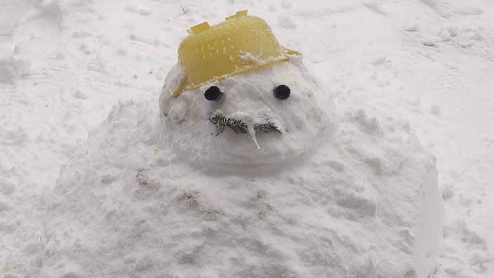 Ein Schneemann trägt ein Nudelsieb als Hut