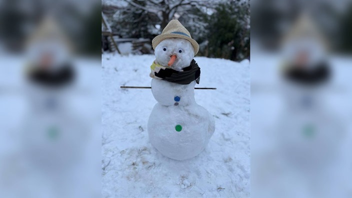 Der Schneemann Hubert mit bunten Knöpfen, einem Schal und einem Sommerhut