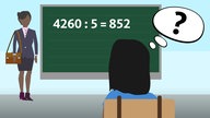 Eine Lehrerin zeigt das Schriftliche Dividieren einer Schülerin an der Tafel 
