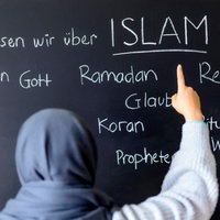 Eine muslimische Schülerin vor einer Tafel mit Begriffen aus dem Islam im Islamunterricht