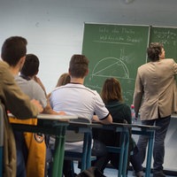 Symbolbild: Ein Lehrer schreibt während des Matheunterrichts einer Abiturklasse an die Tafel.