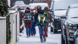 Grundschüler laufen über schneebedeckte Gehwege