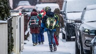 Grundschüler laufen über schneebedeckte Gehwege