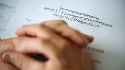 Eine Frauenärztin hat ihre Hände auf der Beratungsbescheinigung gemäß Paragraph 7 Schwangerschaftskonfliktgesetz und Paragraph 219 (2) Strafgesetzbuch gelegt.