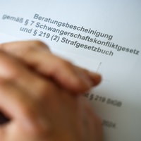Eine Frauenärztin hat ihre Hände auf der Beratungsbescheinigung gemäß Paragraph 7 Schwangerschaftskonfliktgesetz und Paragraph 219 (2) Strafgesetzbuch gelegt.